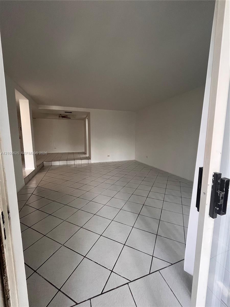 Interior space featuring neutral wall tones, large-format diagonal tile flooring, and a multi-level floor plan with an elevated platform