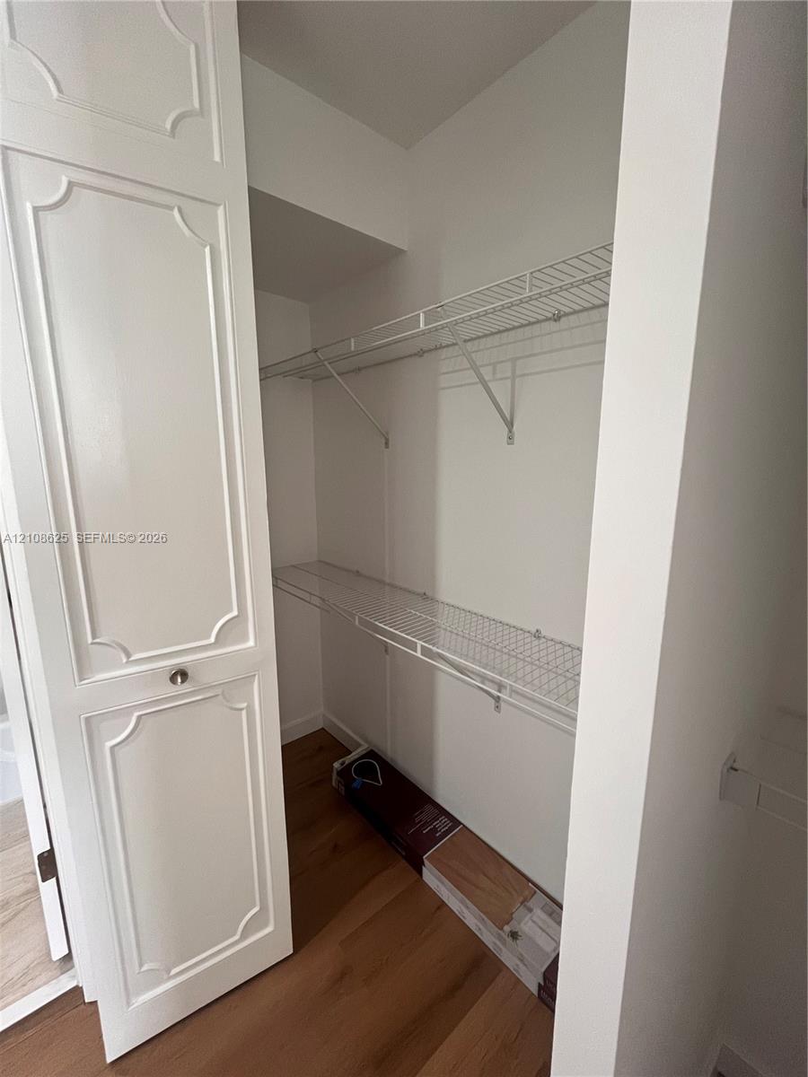 Closet featuring paneled doors, wood-finish flooring, and multi-level white wire shelving