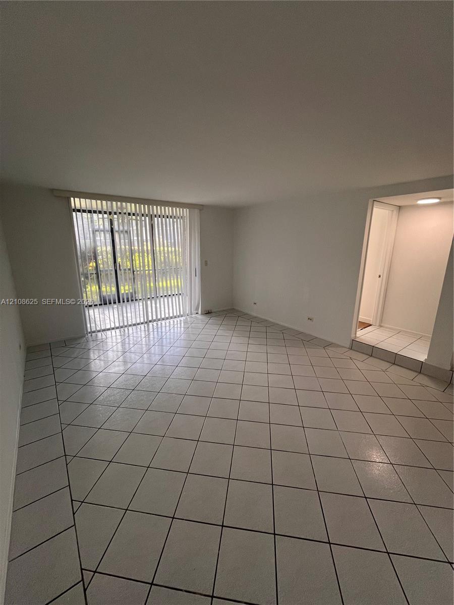 Open interior featuring large-format diagonal tile flooring, sliding glass patio doors with vertical blinds, and recessed ceiling lighting