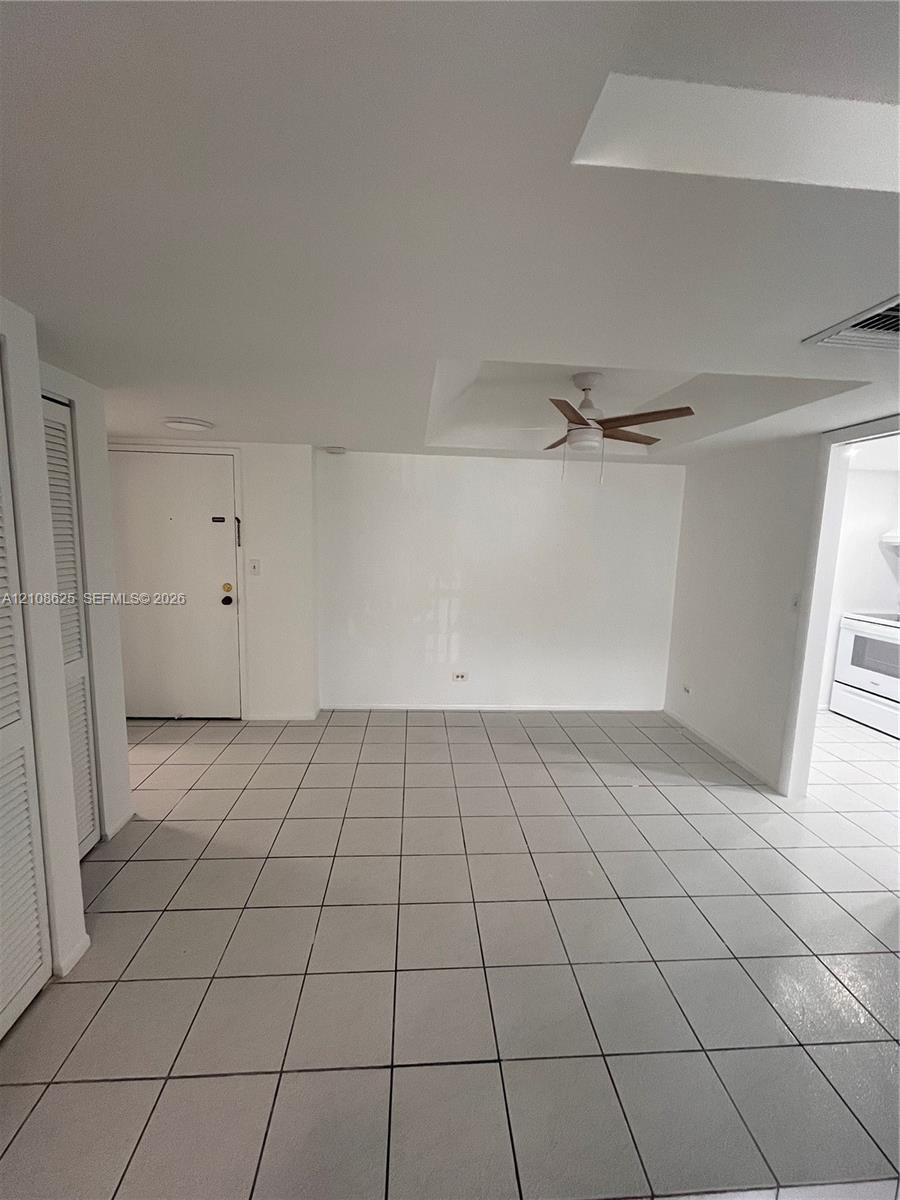 Neutral-toned tiled flooring, recessed ceiling with a mounted fan, and louvered closet doors