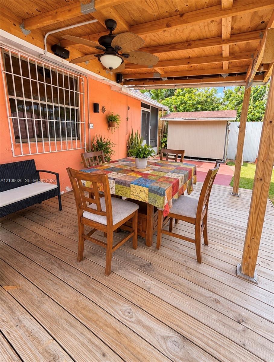 Covered outdoor deck featuring wood-plank flooring, an exposed wood-beam ceiling, and a ceiling-mounted fan with integrated light fixture