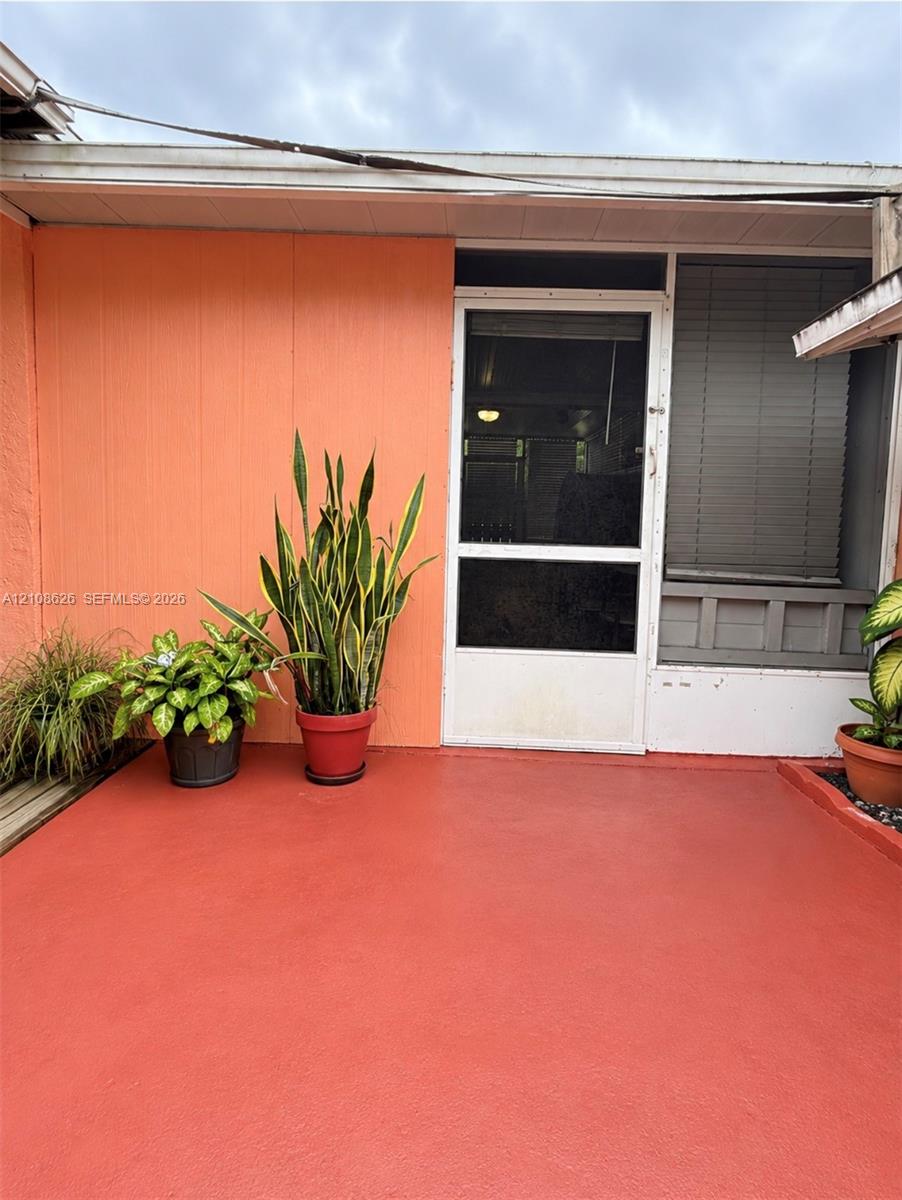 Covered patio featuring a solid-surface floor, vertical panel siding, and a screen door with a transom window