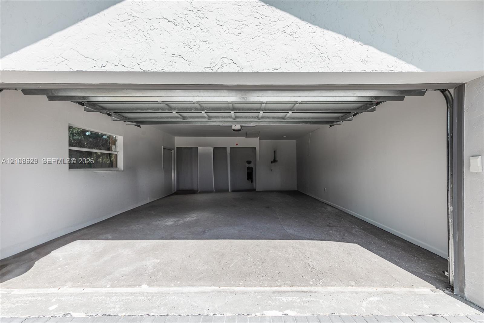 Two-car garage featuring a concrete floor, motorized overhead door, and a side-wall window