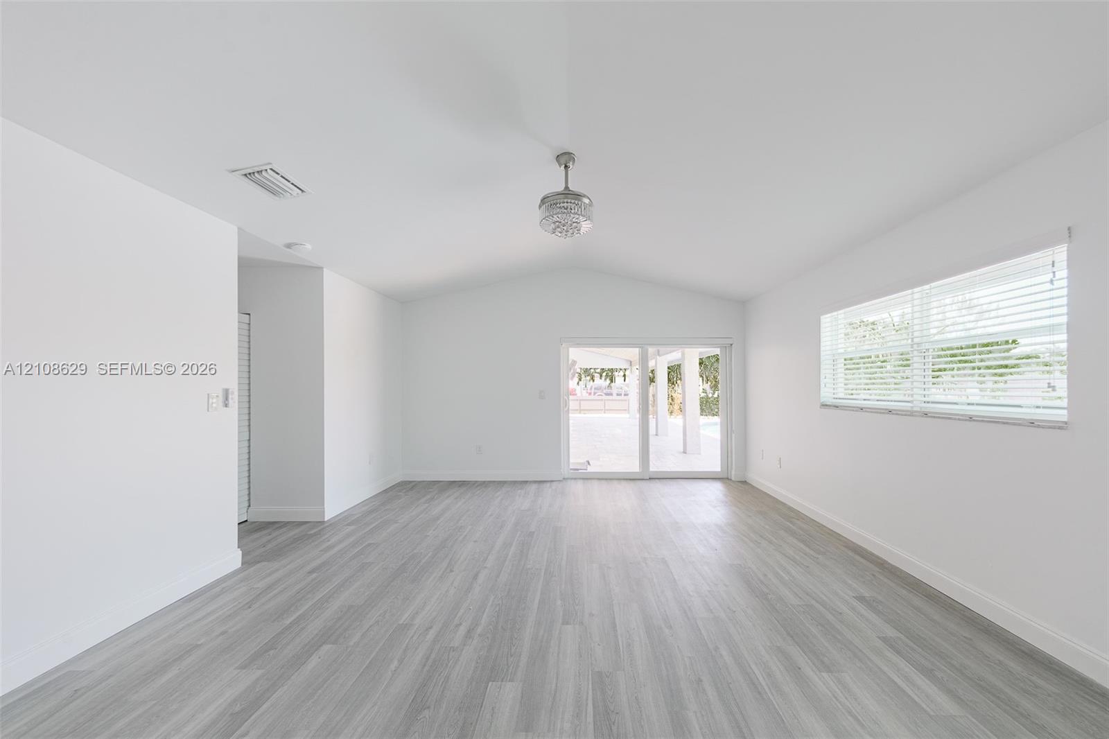 Vaulted ceilings, wood-finish flooring, sliding glass doors, and a decorative ceiling fixture