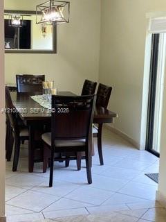 Light-colored ceramic tile flooring, a geometric metal-frame chandelier, and a recessed wall mirror with a dark wood finish frame Light-colored ceramic tile flooring, a geometric metal-frame chandelier, and a recessed wall mirror with a dark wood finish frame