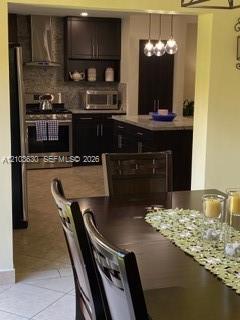 Kitchen featuring dark-finish cabinetry, stone-surface countertops, stainless steel appliances, a center island, and pendant lighting Kitchen featuring dark-finish cabinetry, stone-surface countertops, stainless steel appliances, a center island, and pendant lighting