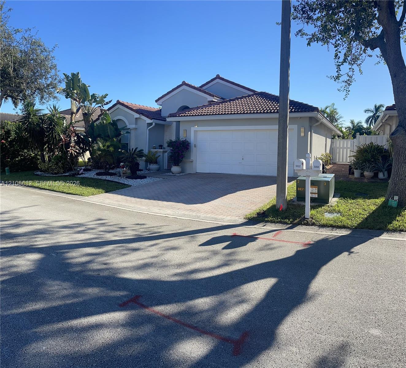 Single-story residence featuring a tile roof, light-toned stucco exterior, two-car garage, and a paved driveway