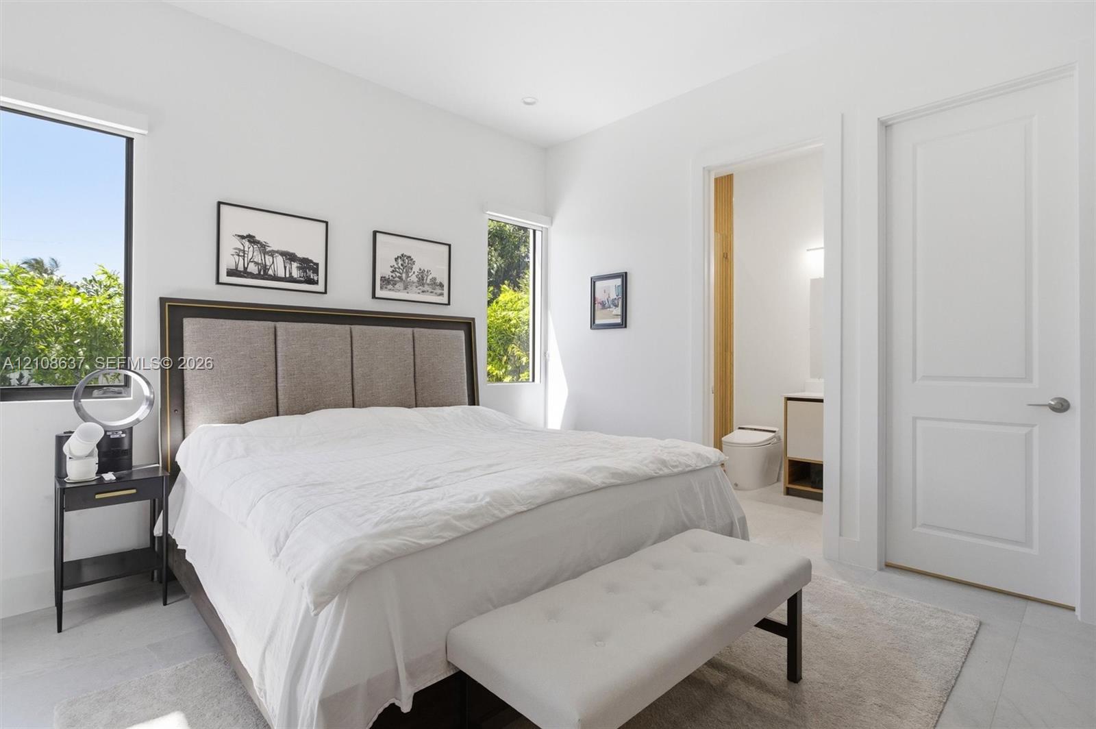 Light-filled space featuring large windows, neutral stone-finish flooring, recessed lighting, and a solid-core interior door