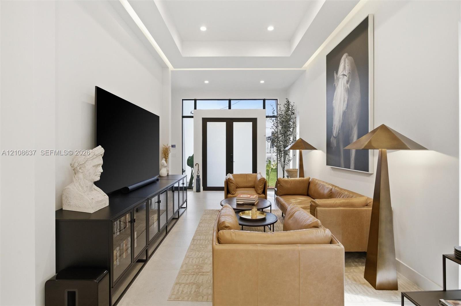 Tray ceiling featuring integrated recessed lighting, smooth finish walls, and glass-paneled double entry doors with dark metal framing