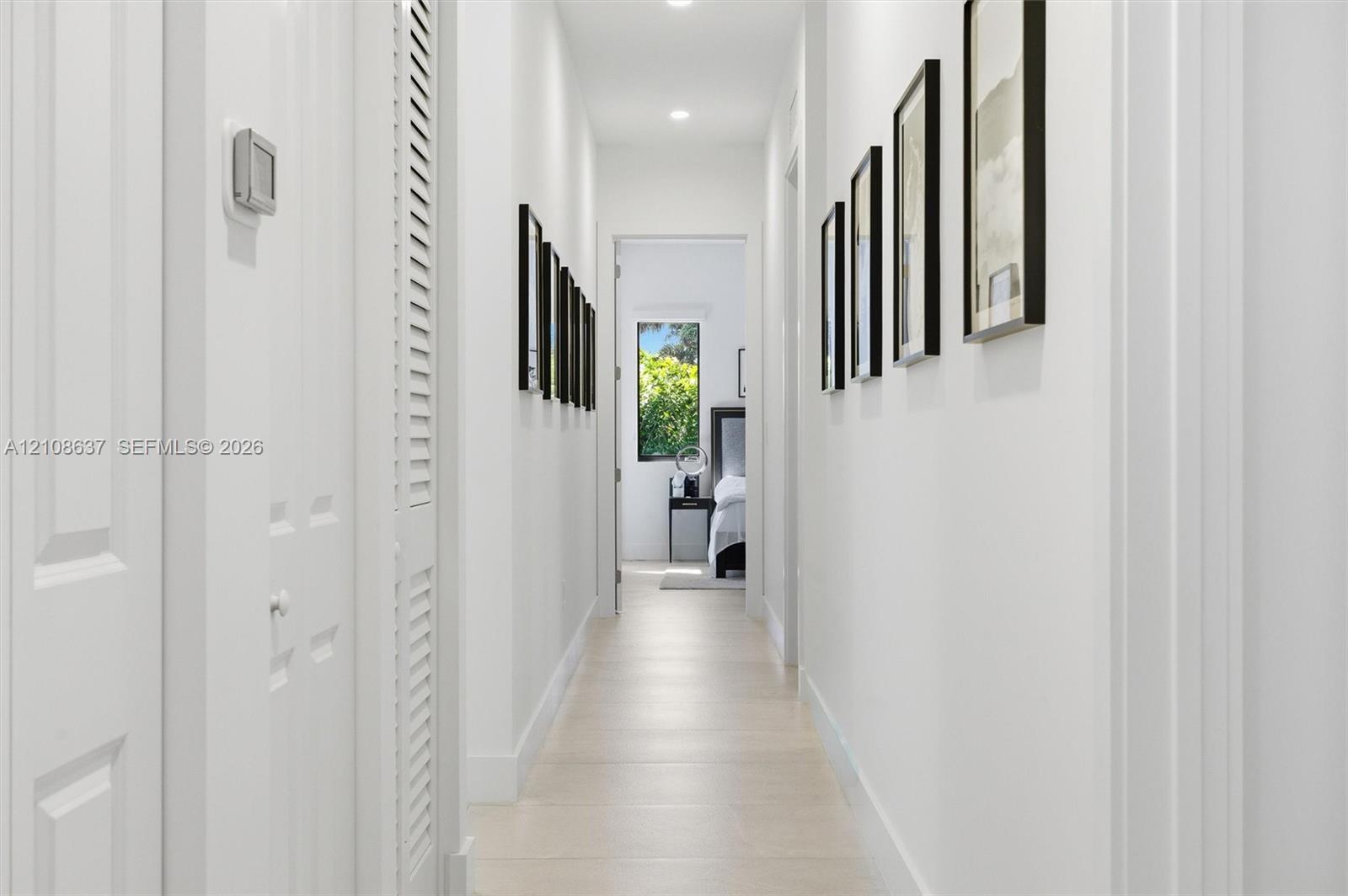 Hallway featuring light-toned tile flooring, recessed ceiling lighting, and louvered-style bi-fold closet doors