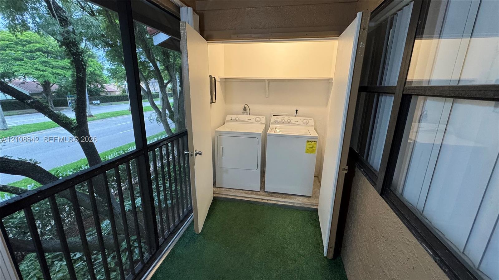 Screened patio enclosure featuring a built-in laundry closet with shelving and sliding glass windows