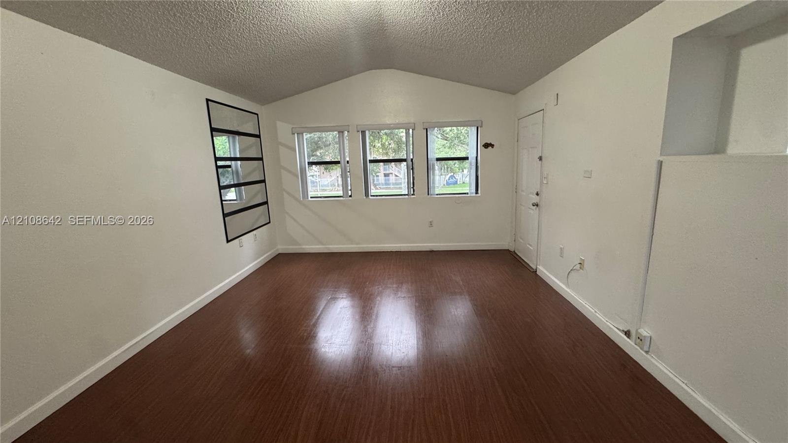 Vaulted ceiling, wood-finish flooring, three-pane window configuration, and recessed wall niche
