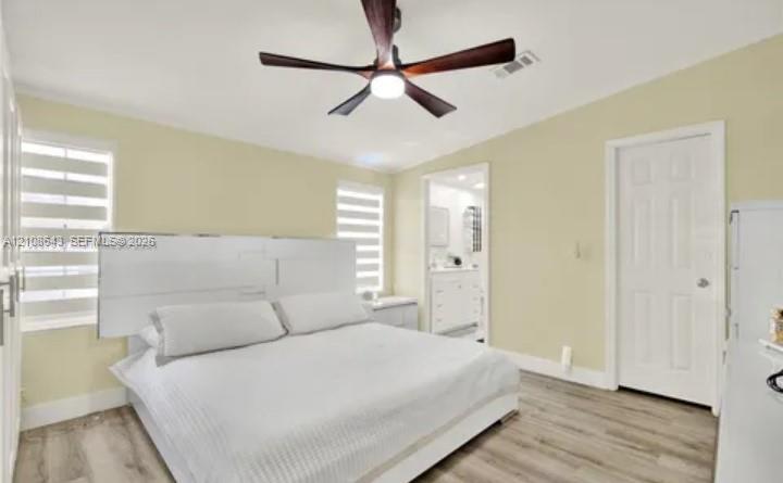 Room featuring wood-finish flooring, a multi-blade ceiling fan with integrated lighting, and dual windows with fitted light-filtering shades