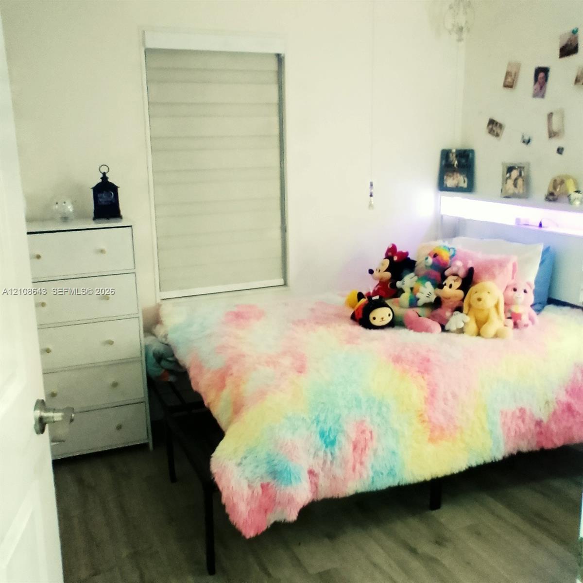 Wood-finish flooring, light-filtering window shade, and built-in headboard featuring integrated accent lighting