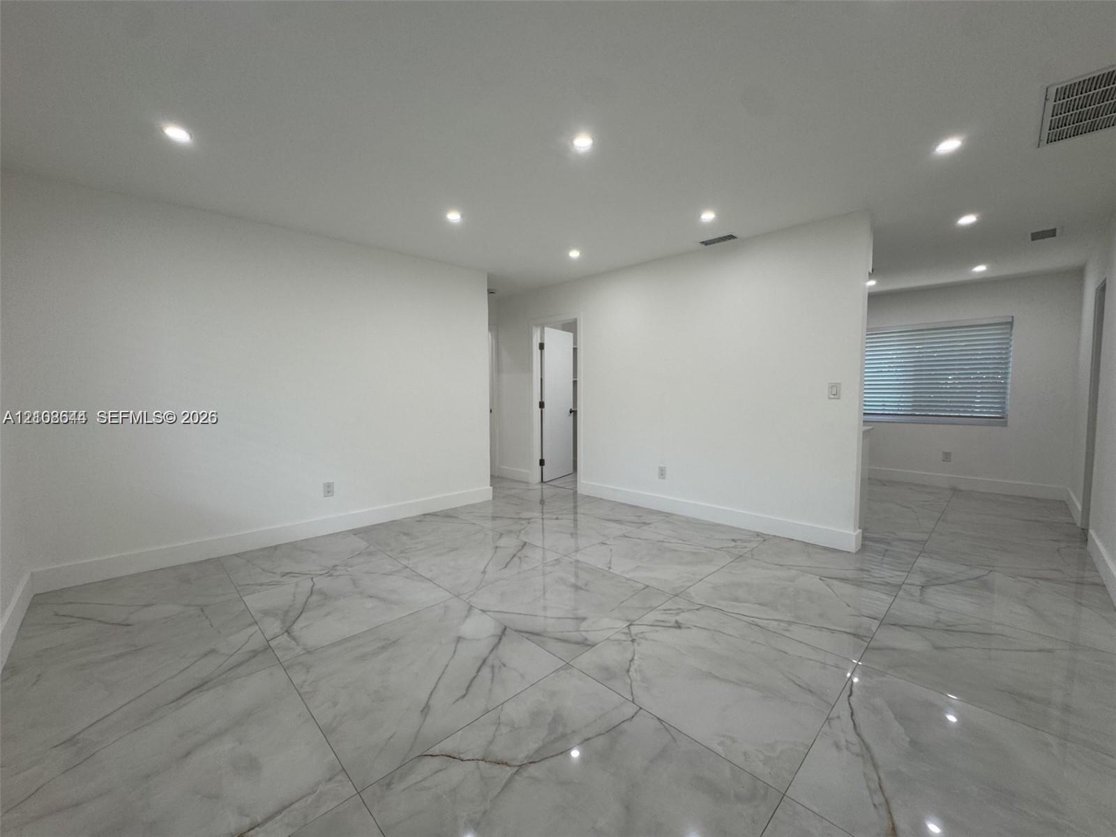 Open-concept interior featuring large-format polished stone-finish floor tiles and recessed ceiling lighting