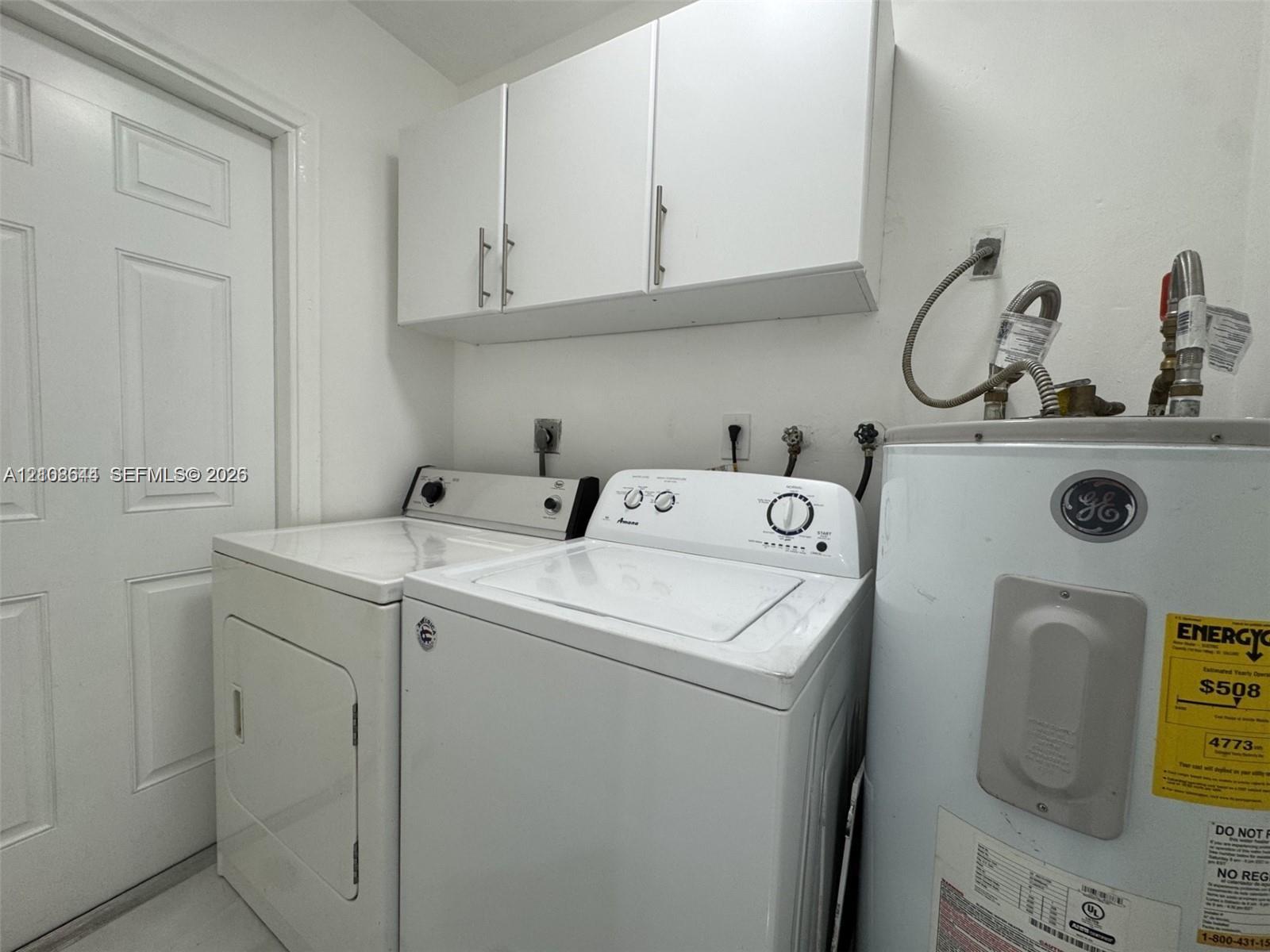 Utility area featuring white flat-panel upper cabinetry, a six-panel door, and dedicated washer and dryer hookups