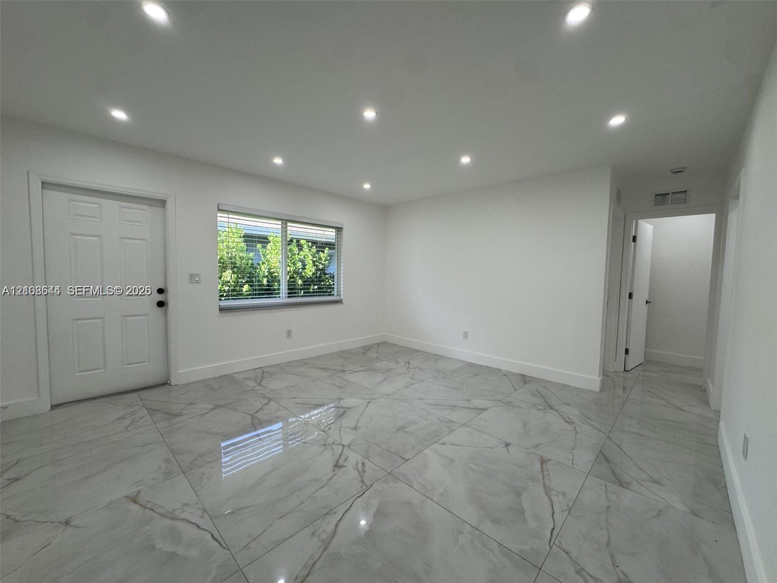 Large-format tile flooring, recessed ceiling lighting, and six-panel interior door