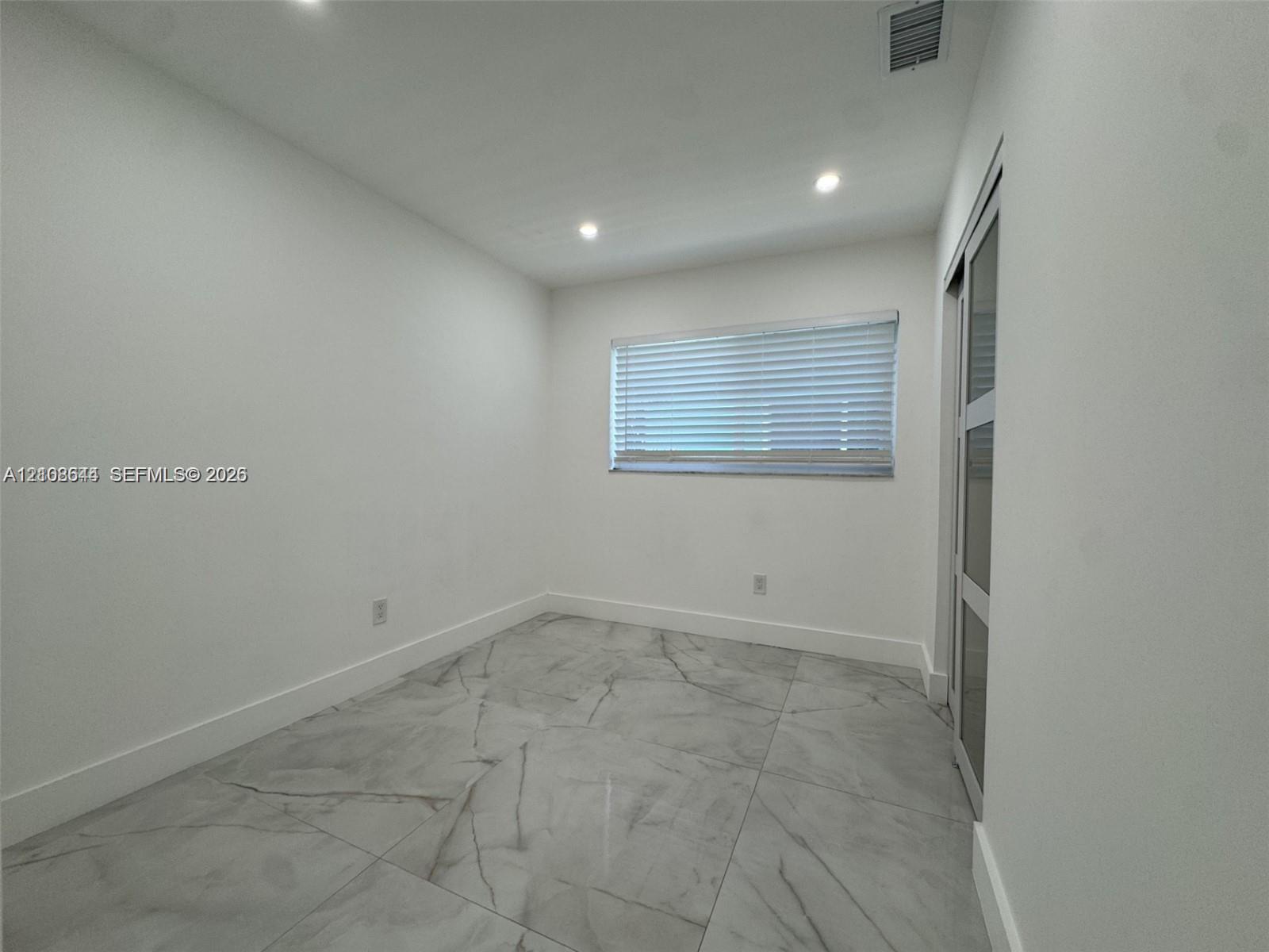 Interior space featuring large-format tile flooring, recessed lighting, and a sliding door with glass panels