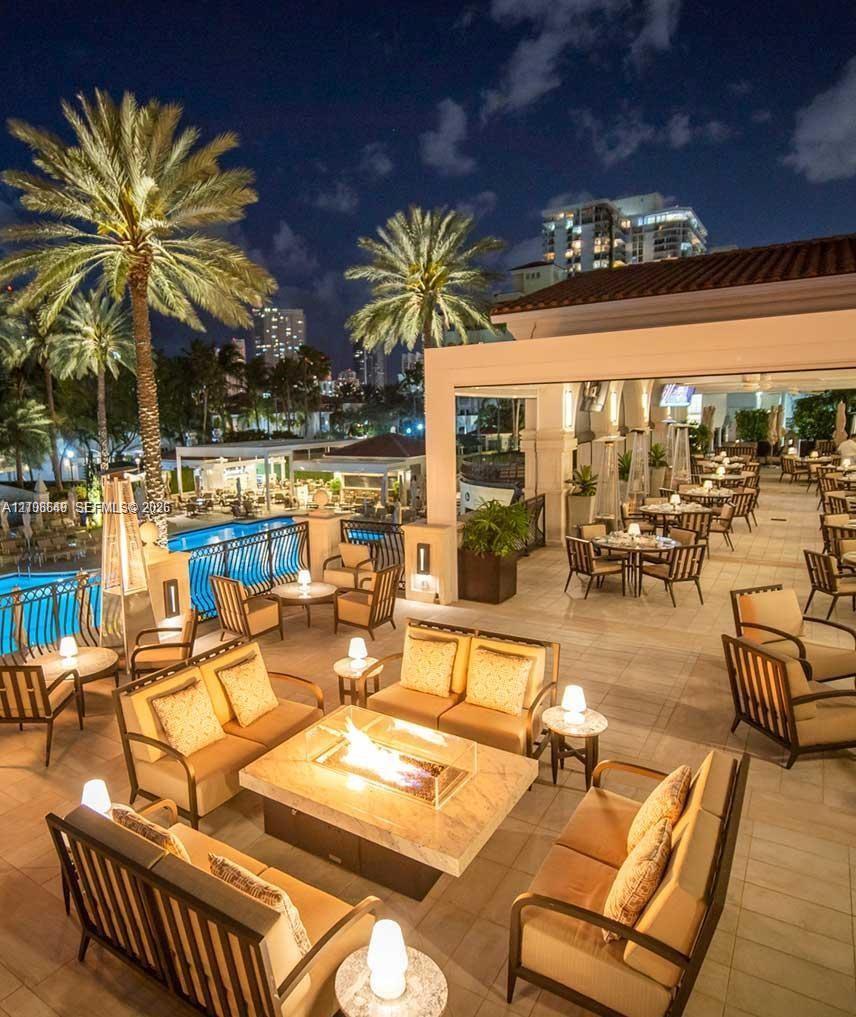 Expansive outdoor terrace featuring stone flooring, a built-in fire pit with a stone surround, and an integrated swimming pool with metal safety railing