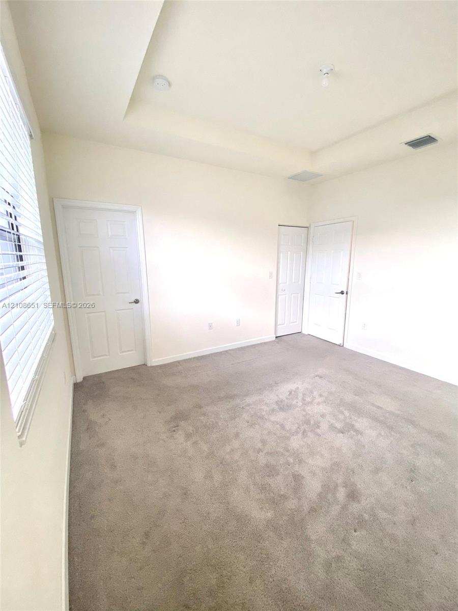 Interior space featuring a recessed tray ceiling, wall-to-wall carpeting, and two six-panel interior doors