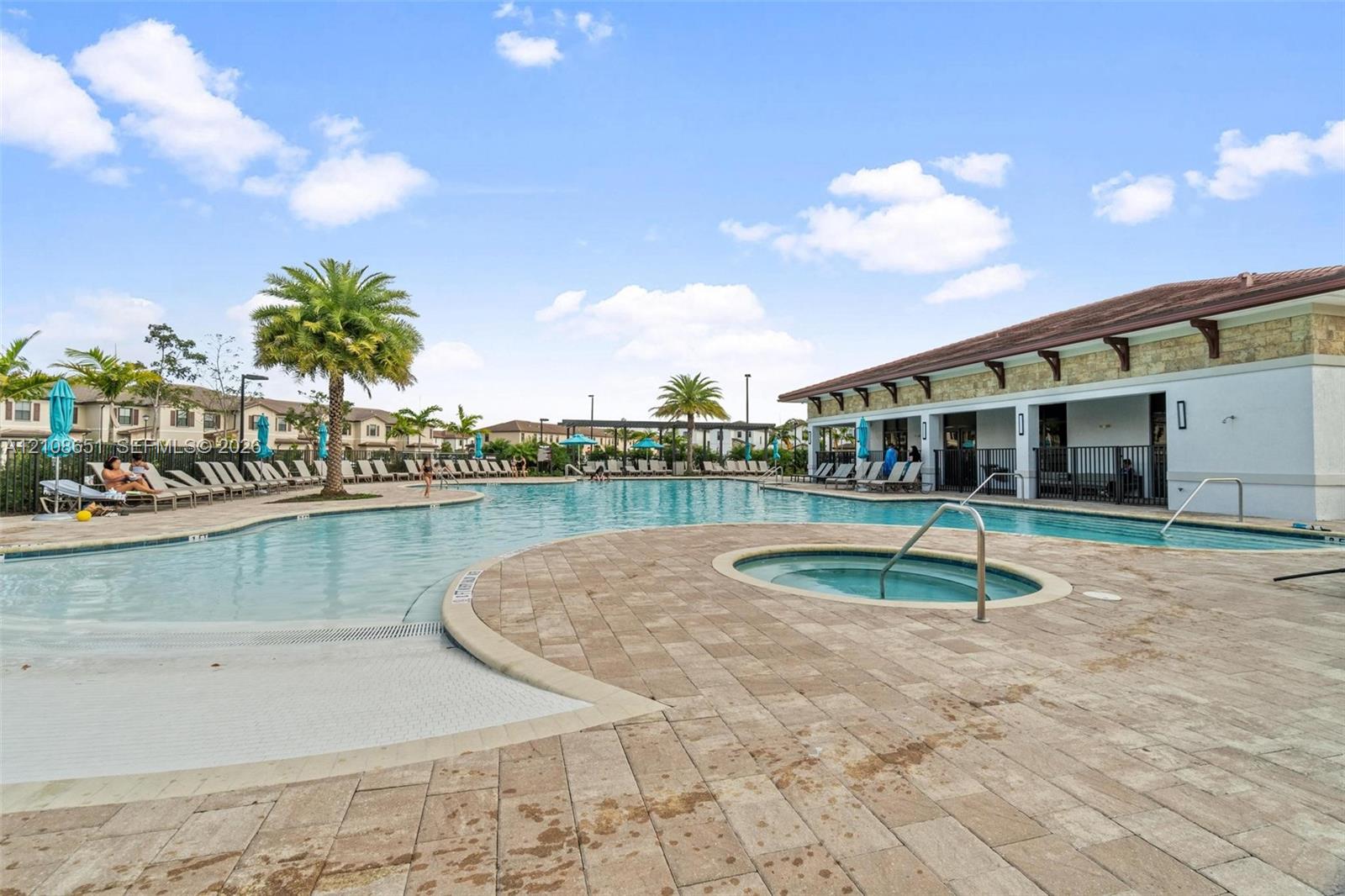 Community swimming pool featuring a zero-entry basin, integrated spa, and extensive paver decking