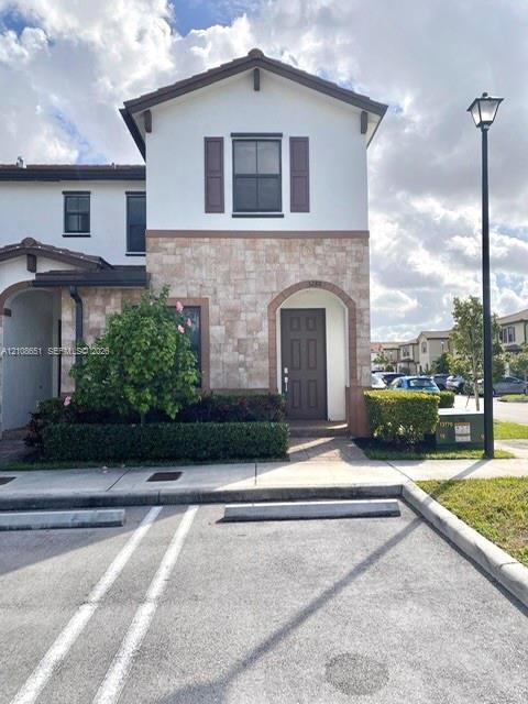 Exterior featuring stone veneer facade, neutral stucco finish, decorative shutters, and an arched entry Exterior featuring stone veneer facade, neutral stucco finish, decorative shutters, and an arched entry