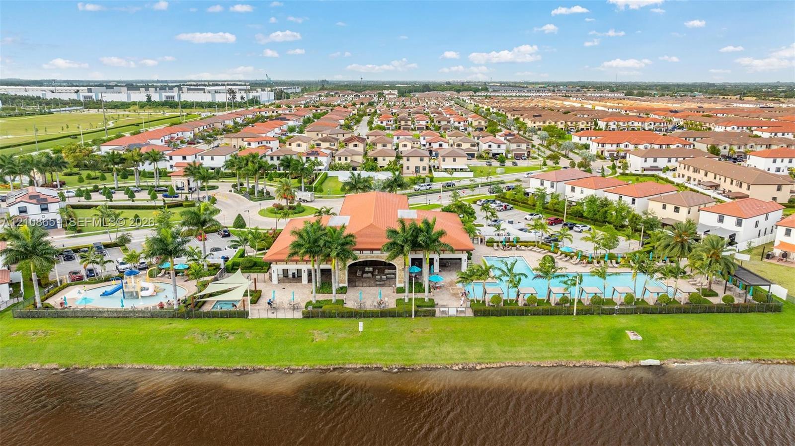 Community clubhouse featuring a swimming pool, childrens splash area with slide, paved patio space, and direct waterfront access