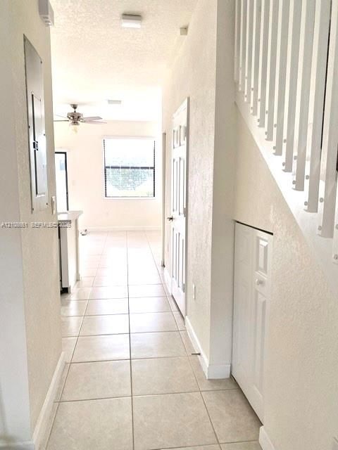 Ceramic tile flooring, white staircase with vertical balusters, and under-stair storage closet