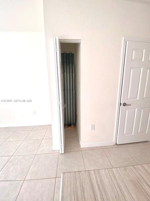 Neutral ceramic floor tiling, six-panel interior door, and built-in closet storage space