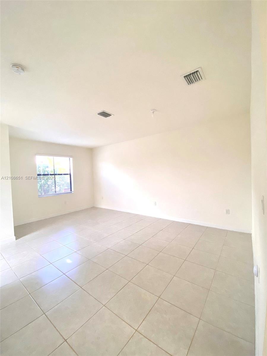 Neutral-toned ceramic tile flooring, crisp white walls, and a single-pane window with a grid pattern