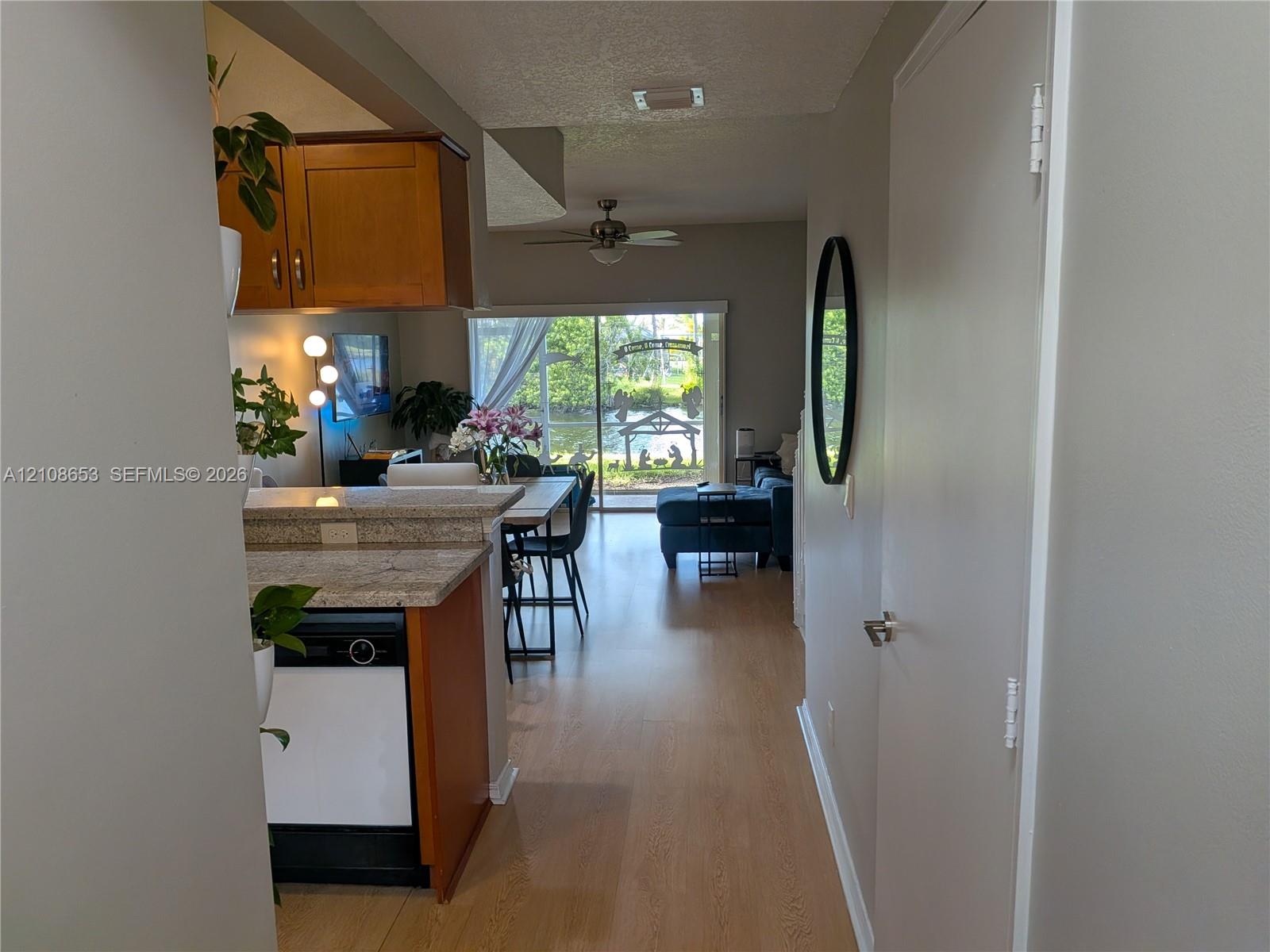 Wood-finish flooring, kitchen cabinetry, stone-finish countertops, ceiling fan, and sliding glass door Wood-finish flooring, kitchen cabinetry, stone-finish countertops, ceiling fan, and sliding glass door
