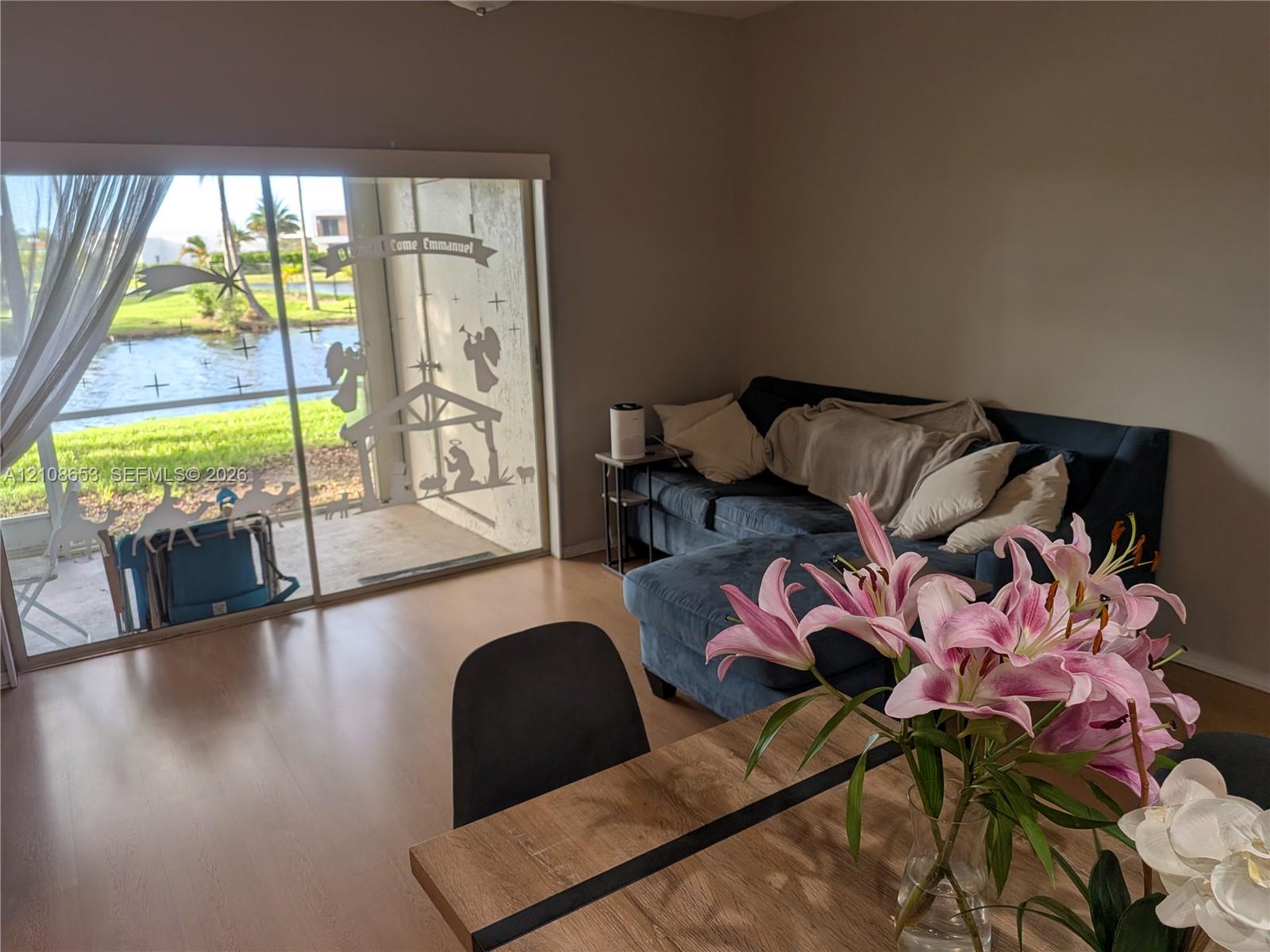 Large sliding glass doors opening to a concrete patio with water frontage and wood-finish flooring Large sliding glass doors opening to a concrete patio with water frontage and wood-finish flooring