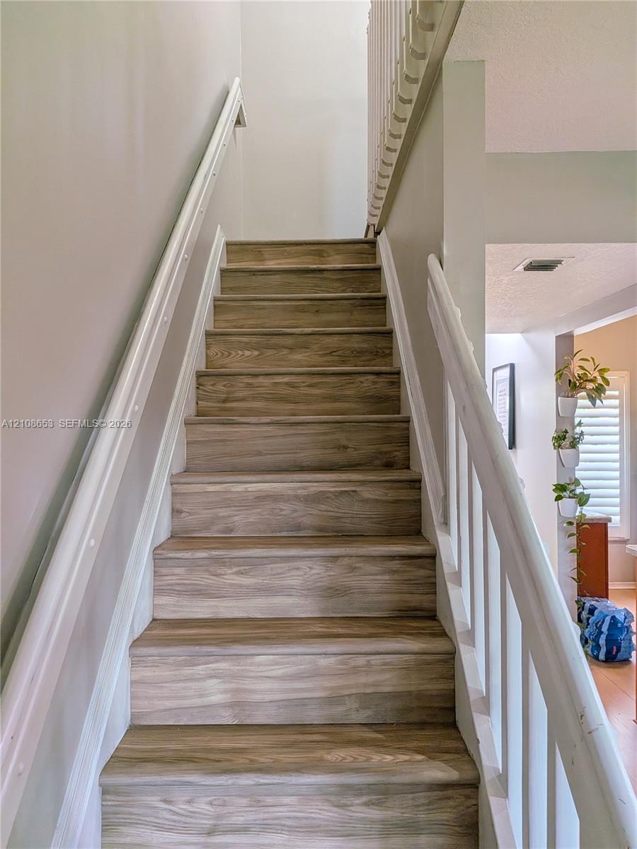 Staircase featuring wood-finish treads and white painted handrails with balusters