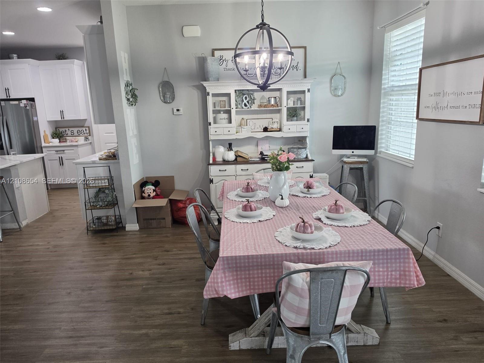 Open-concept space featuring wood-finish flooring, a spherical metal chandelier, built-in cabinetry, recessed lighting, and windows with integrated blinds