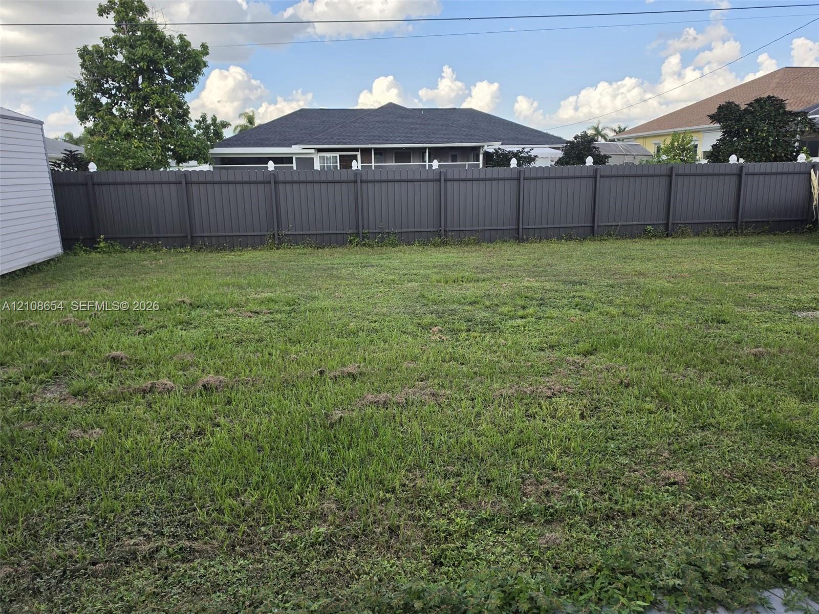 Expansive backyard featuring an open grass lawn and a full-perimeter privacy fence