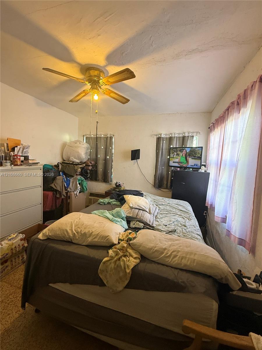 Room featuring a ceiling fan, multiple windows, and smooth-surface flooring Room featuring a ceiling fan, multiple windows, and smooth-surface flooring