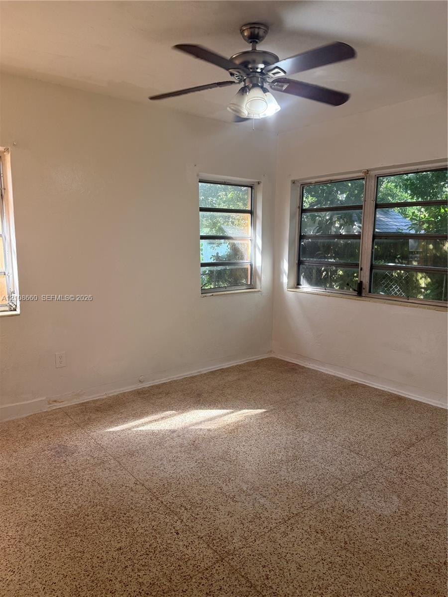 Interior space featuring light-toned tile flooring, multi-pane casement windows, and a ceiling-mounted fan with integrated light fixture Interior space featuring light-toned tile flooring, multi-pane casement windows, and a ceiling-mounted fan with integrated light fixture