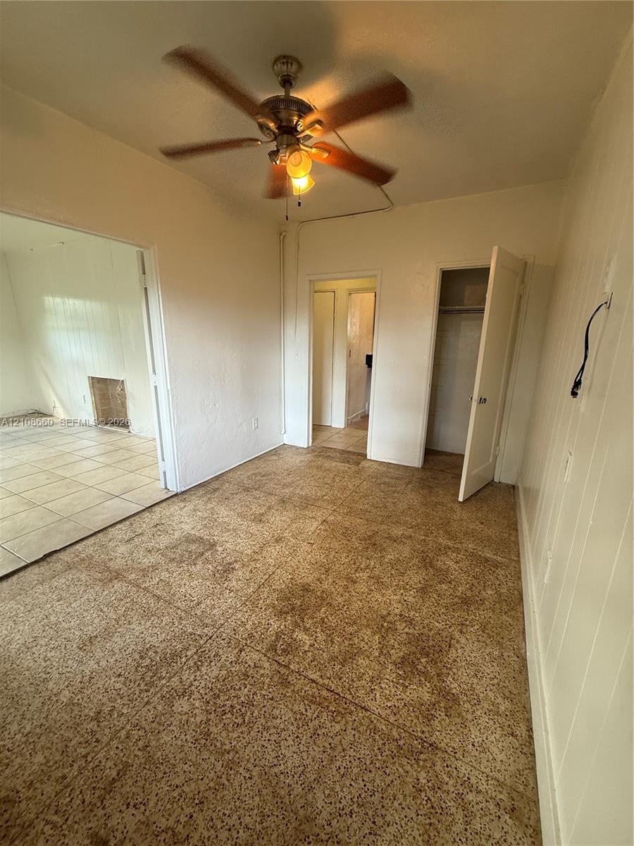 Room featuring textured flooring, ceiling fan with integrated lighting, and built-in closet storage