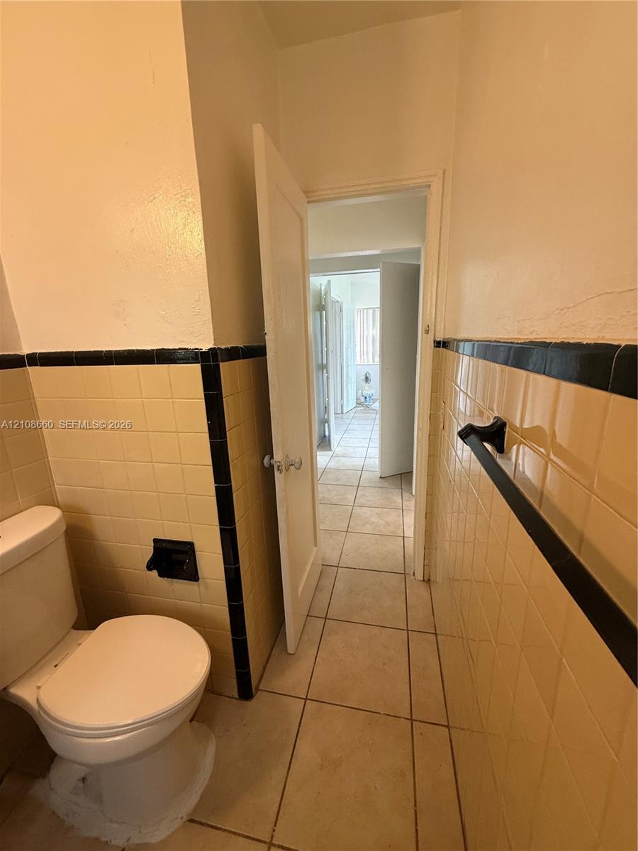 Ceramic wall tile featuring a decorative black border, tile flooring, and a wall-mounted towel bar