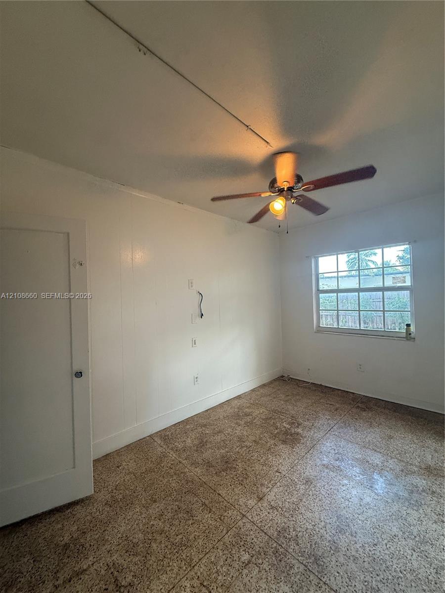 Room featuring light-toned flooring, a multi-pane window, and a ceiling fan with integrated lighting