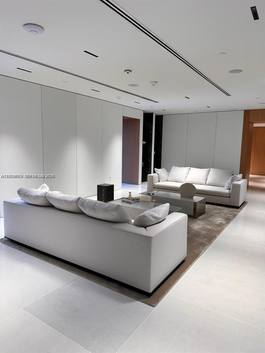 Large-format stone flooring, recessed linear lighting, minimalist flush-panel wall treatments, and integrated ceiling speakers