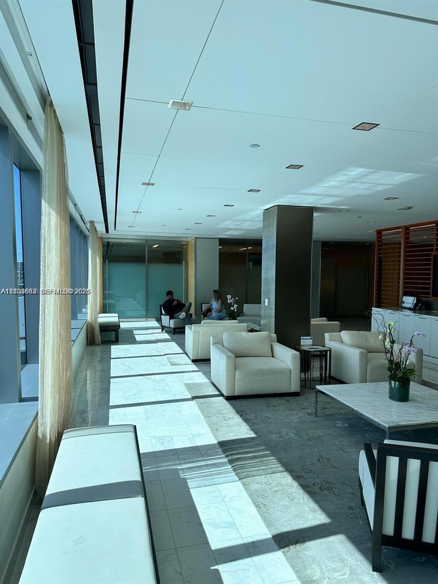 Open-concept common area featuring floor-to-ceiling windows, polished stone flooring, recessed ceiling lighting, and a prominent structural pillar