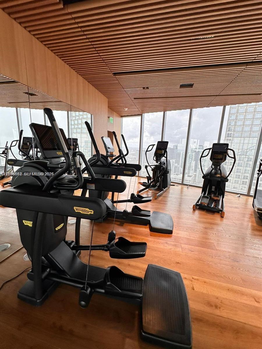 Fitness center featuring floor-to-ceiling windows, wood-finish flooring, and a linear slat ceiling design