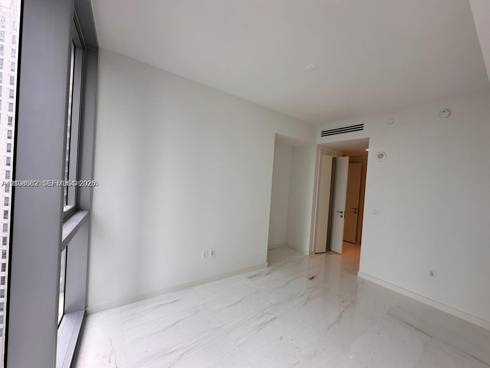 Floor-to-ceiling windows with metal framing, stone-finish flooring, and neutral wall tones