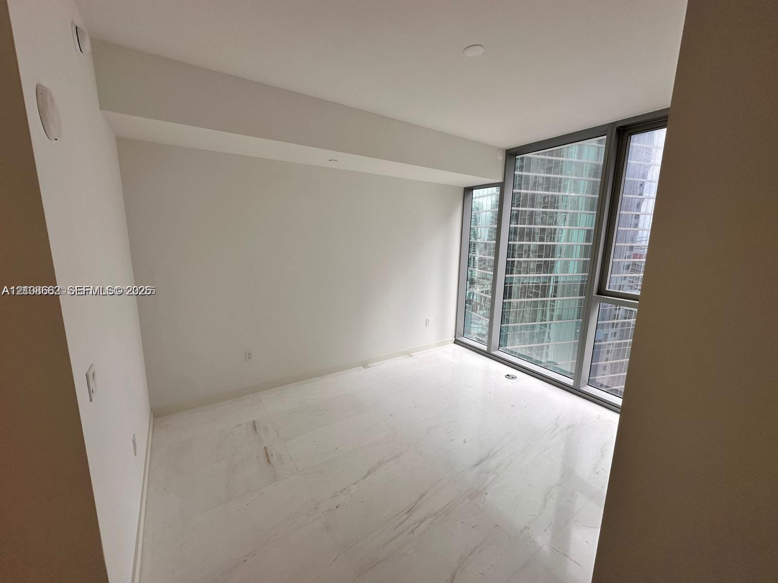 Interior room featuring floor-to-ceiling windows with metal framing and polished stone flooring