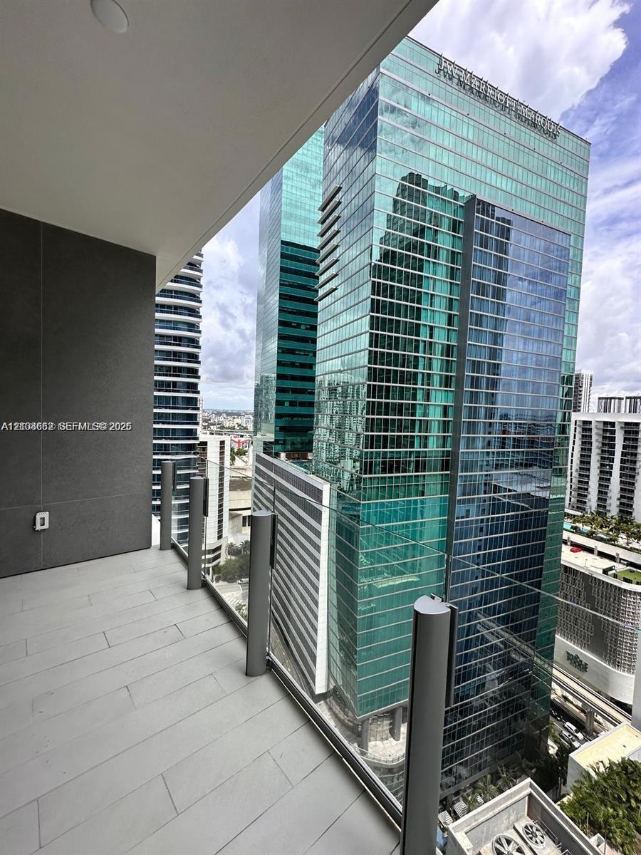 Covered balcony featuring grey tile flooring, recessed ceiling lighting, and a glass panel railing