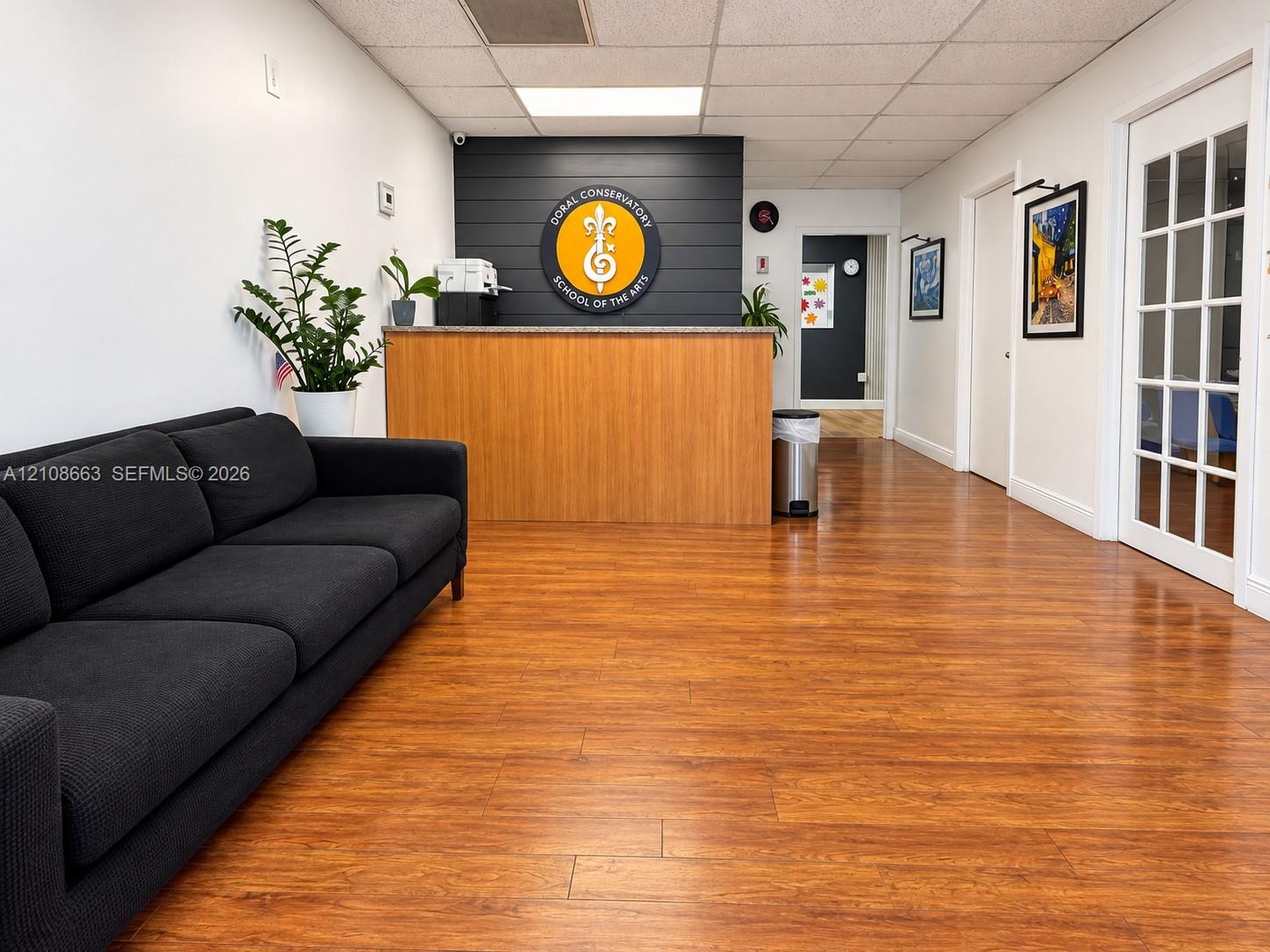 Reception area featuring wood-finish flooring, a wood-finish built-in desk with a stone countertop, a charcoal shiplap accent wall, and a multi-pane glass door