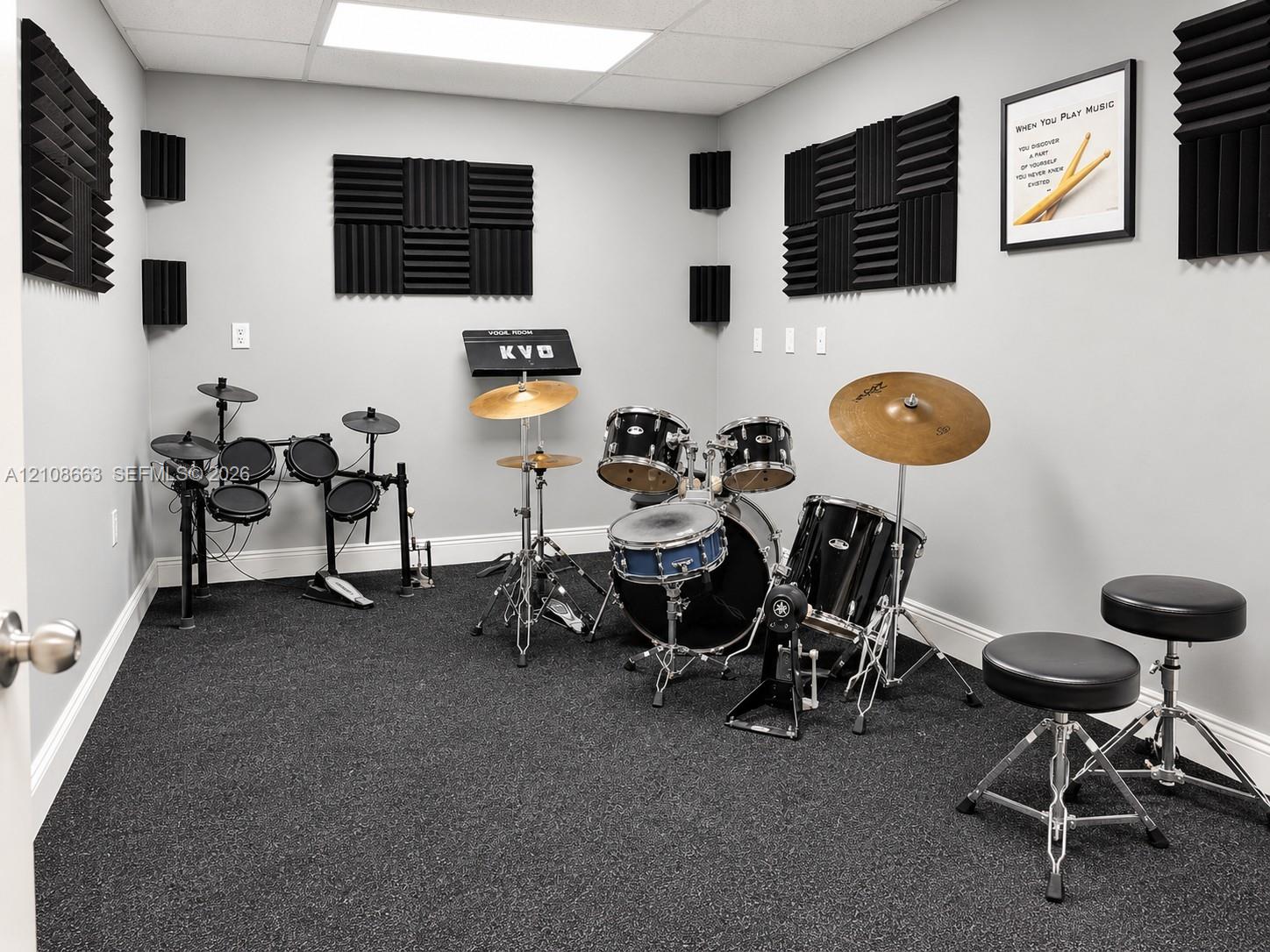 Interior room featuring dark carpeting, neutral gray wall paint, and integrated acoustic wall paneling
