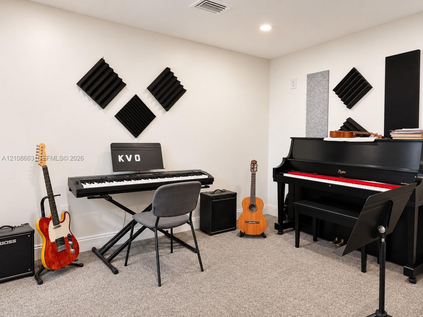 Dedicated room featuring wall-mounted sound-attenuation panels, neutral wall finish, and carpeted flooring
