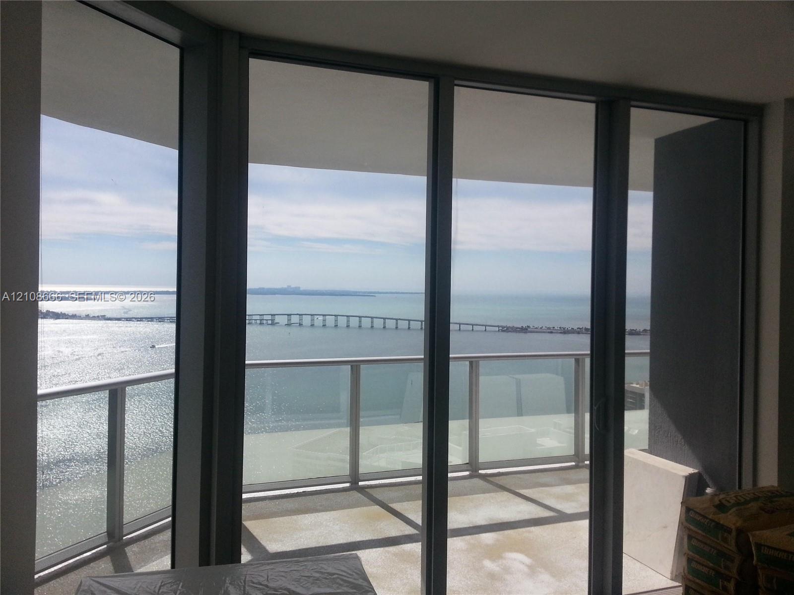 Floor-to-ceiling glass panel windows, metal-framed sliding glass doors, and a private balcony with a glass railing Floor-to-ceiling glass panel windows, metal-framed sliding glass doors, and a private balcony with a glass railing